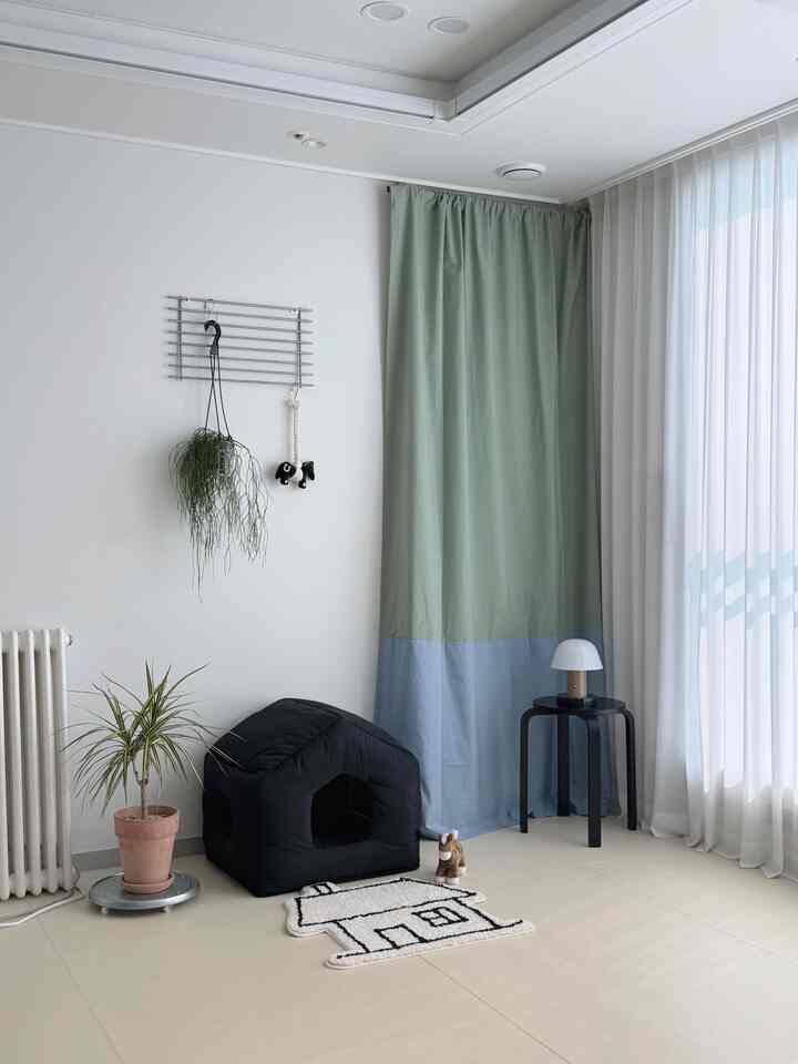 ホワイトとブラックが調和する清潔感のあるリビングの一角、ペットハウスと植物が配置された落ち着いたミニマルな空間