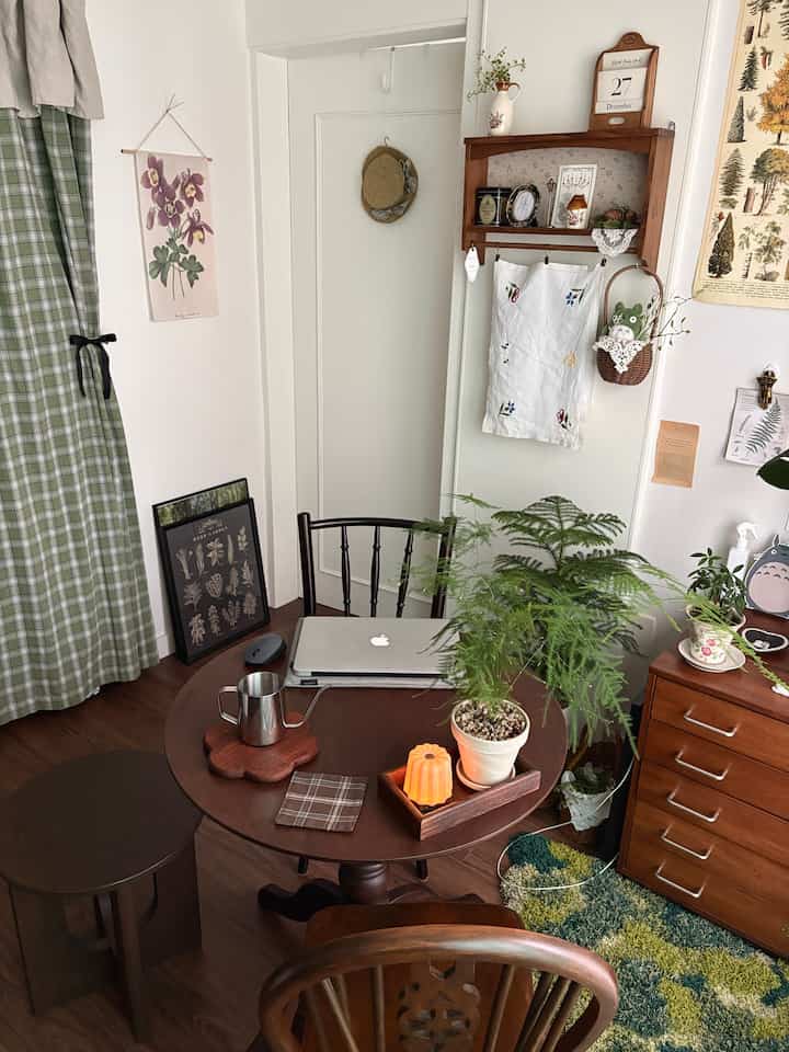 ウッド調とグリーンが映える二人用多目的ダイニングスペース、ヴィンテージスタイルとナチュラルな植物装飾が調和した落ち着いた雰囲気のインテリア