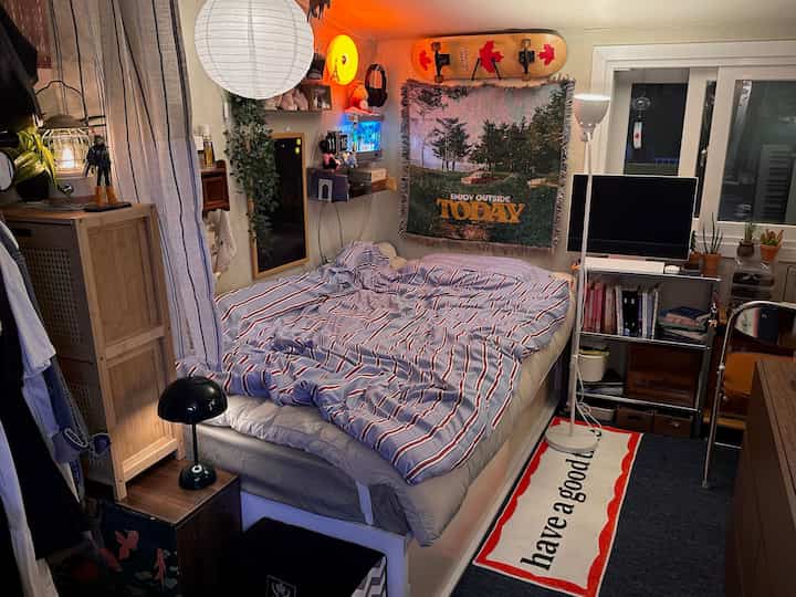 Cozy bedroom with warm wood tones and silver accents, featuring bed, shelves, and dog accessories in a compact space