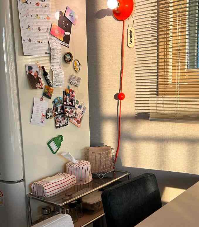 Cozy kitchen space with warm beige walls, white refrigerator, black chair, and vibrant red wall light