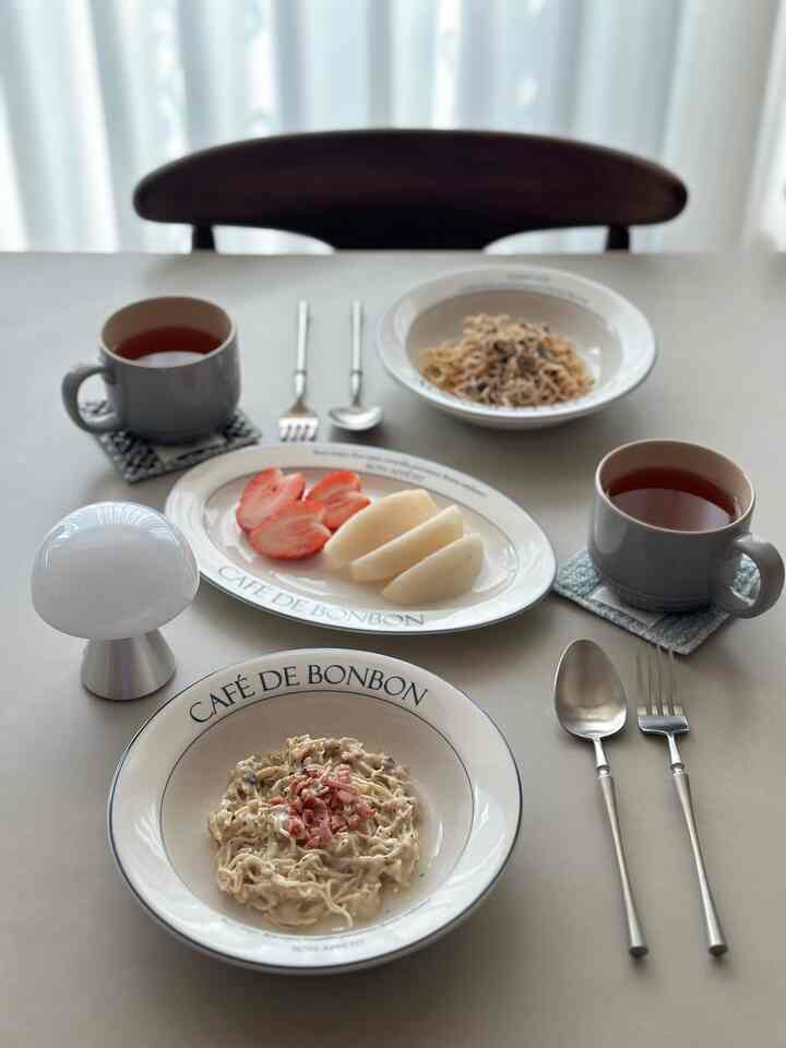 白とグレーのトーンのテーブルにカフェ風の食器とカトラリーが整然と配置されたおうちカフェスタイルのインテリア