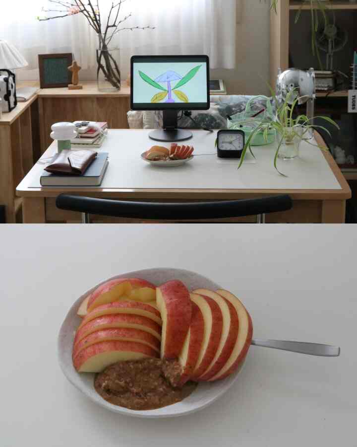 ホワイトと木目調の調和があるホームオフィス、白いデスクにモニターとリンゴの盛り皿が置かれた清潔感のある作業空間