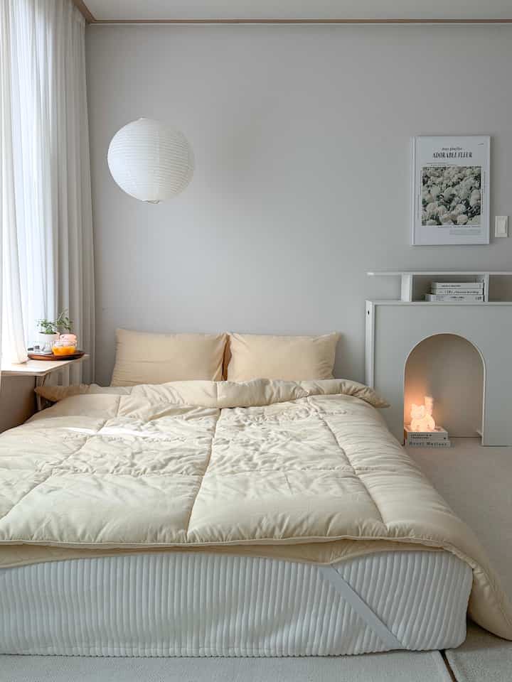 やわらかなベージュとホワイトトーンの寝室、クイーンサイズベッドとシンプルなインテリアが調和した落ち着いた空間