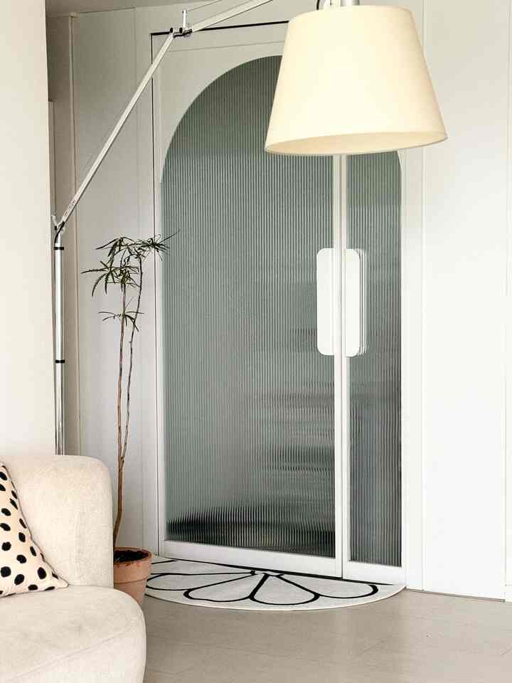 白とナチュラルカラーのリビング、クリーム色のソファとフロアランプが配置されたシンプルでモダンな空間