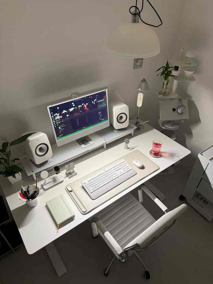 モノトーンのホワイト色調のコンパクトなホームオフィス、ホワイトデスクとオフィスチェア、スピーカー2台、モニターが配置されたモダンな作業空間