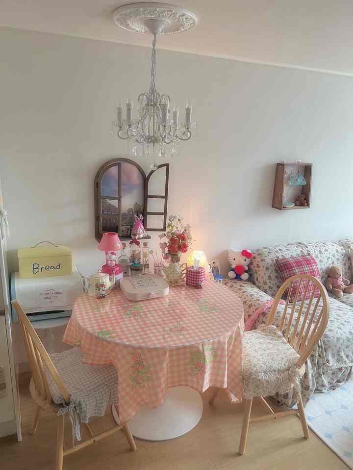 ピンクのギンガムチェックのテーブルクロスがあるダイニングルーム、花瓶とシャンデリアが配置された雰囲気のあるインテリア