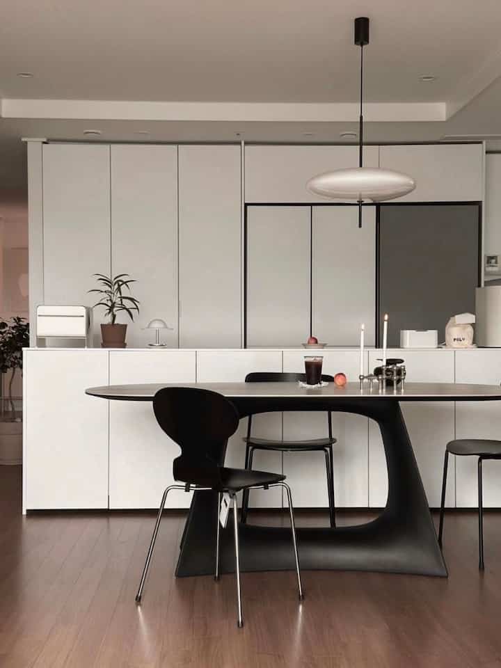 ホワイトとブラック、ウッドトーンが調和したモダンなキッチン空間、黒のダイニングテーブルと椅子が配置された洗練された印象的なインテリア