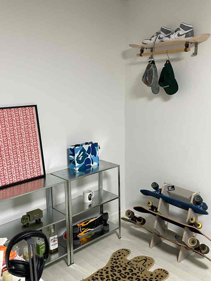 Small room with white walls and natural color flooring, featuring skateboard racks and metal shelves in a clean skateboard decor space