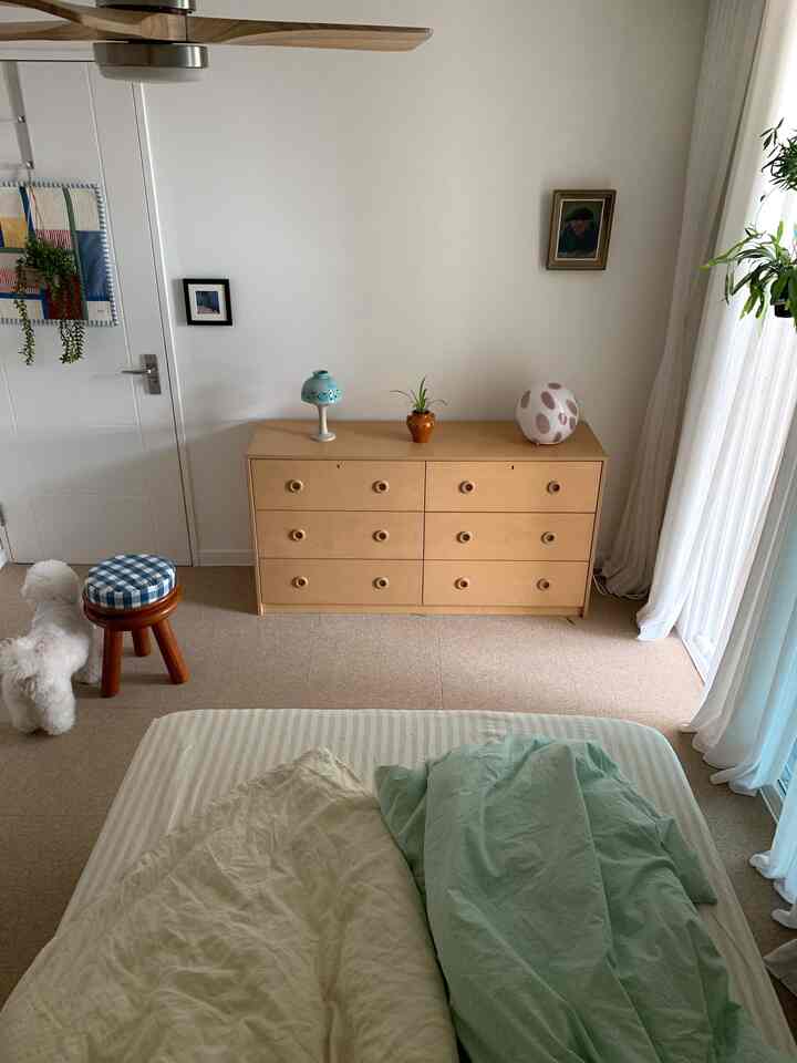 明るい木目調家具とミント色の寝具が配置された雰囲気のある寝室