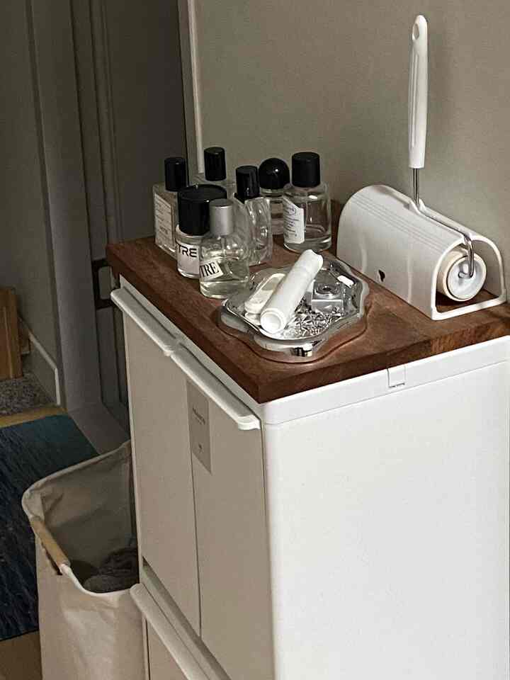 ナチュラルカラーのキャビネット、木製の天板に香水や日用品が整然と配置されたシンプルで落ち着いた空間