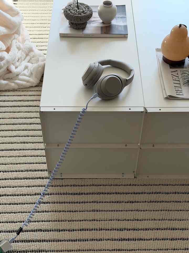 白と青のトーンのリビングホームオフィス、清潔なデスクにヘッドホンとオブジェが配置された雰囲気のあるインテリア