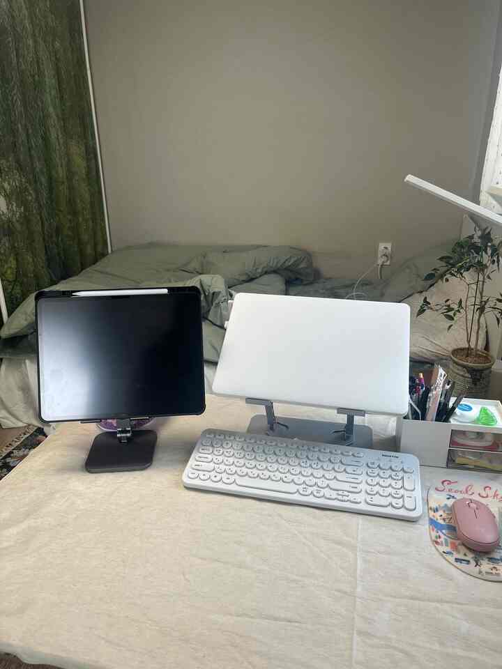 ベージュのリネンテーブルクロスが敷かれた寝室のデスクにリモートワーク用のキーボードとタブレットが配置されたシンプルなホームオフィス空間