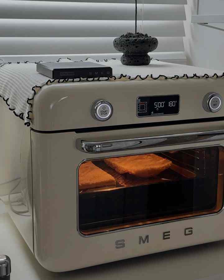 スカイブルーの色調が印象的なキッチン、SMEGのオーブンとブラインドが配置されたシンプルな雰囲気のインテリア