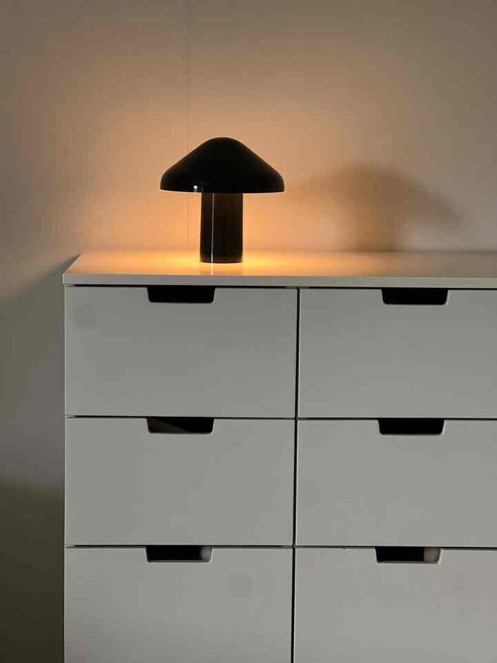 白いチェストの上に黒いテーブルランプが置かれたシンプルで落ち着いた空間
