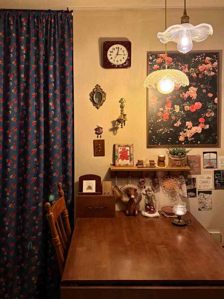 木目調のレトロなダイニング、花柄のカーテンとヴィンテージ照明が配置された雰囲気のある空間