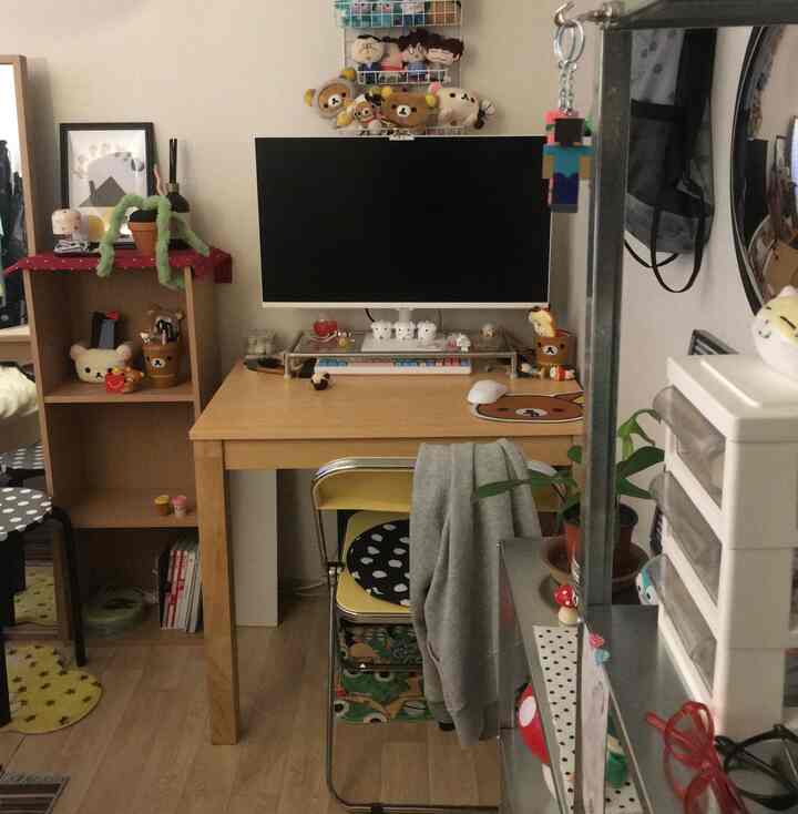 ナチュラルな木目調と白い壁のコンパクトなホームオフィス、机とモニター、収納家具が配置された整った小さな部屋のインテリア