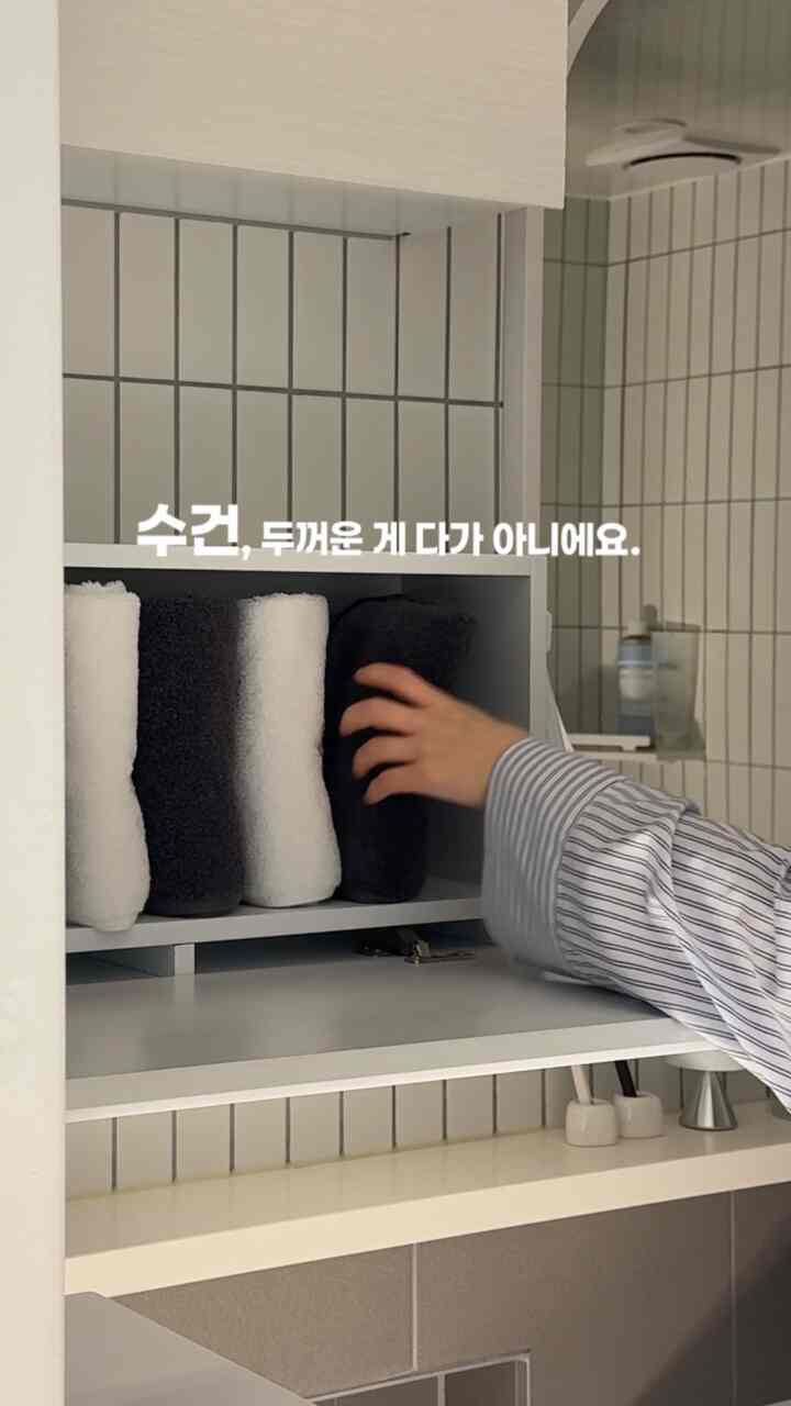 モノトーンの浴室キャビネットに白と黒のタオルがきちんと並べられた、清潔感のある浴室インテリア