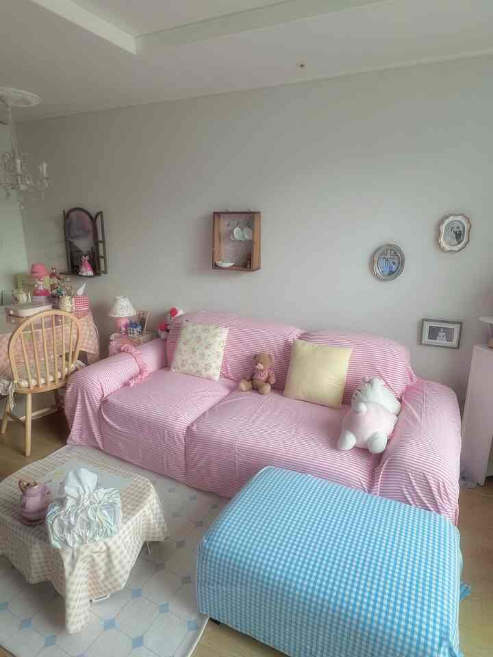 パステルピンクとブルーの色調のリビング、居心地の良いソファとかわいい装飾が配置された温かみのあるインテリア