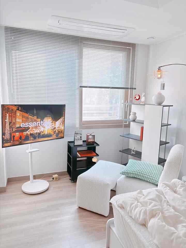 Small modern living room in white and black tones featuring blinds, floor lamp, and textured sofa with a clean atmosphere