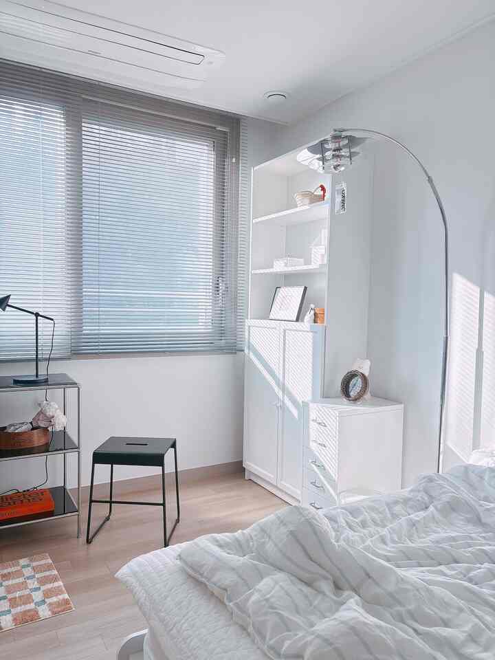 White-toned bedroom featuring a large cabinet and blinds, creating a clean and modern space