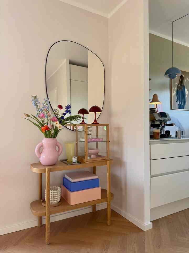 Cozy corner next to kitchen featuring soft pastel and wood tones with a table adorned by vase with flowers and table lamps