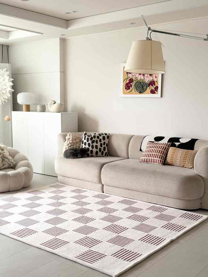 ベージュとホワイトのトーンが調和するリビング、セクショナルソファとパターンラグ、フローラルアートが配置された落ち着いた雰囲気のインテリア