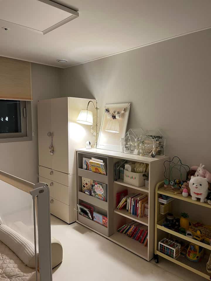 白とナチュラルトーンを基調にした、赤ちゃんと子供の収納棚がある居心地の良い子供部屋風の空間