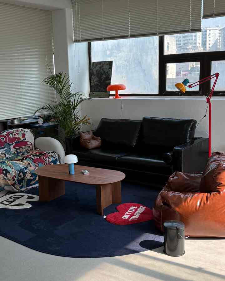 ネイビートーンのラグとブラウンのビーンバッグソファ、黒のレザーソファが配置されたモダンで落ち着いたリビング