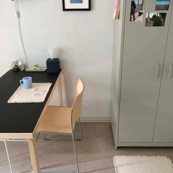 白と黒のトーンでまとめられた一人暮らし用の狭くコンパクトな部屋、机と収納キャビネットが配置されたミニマルな空間