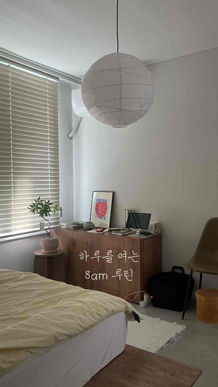 ベージュと白の落ち着いた色調の寝室、窓のブラインドと木製のチェストが配置された雰囲気のあるインテリア