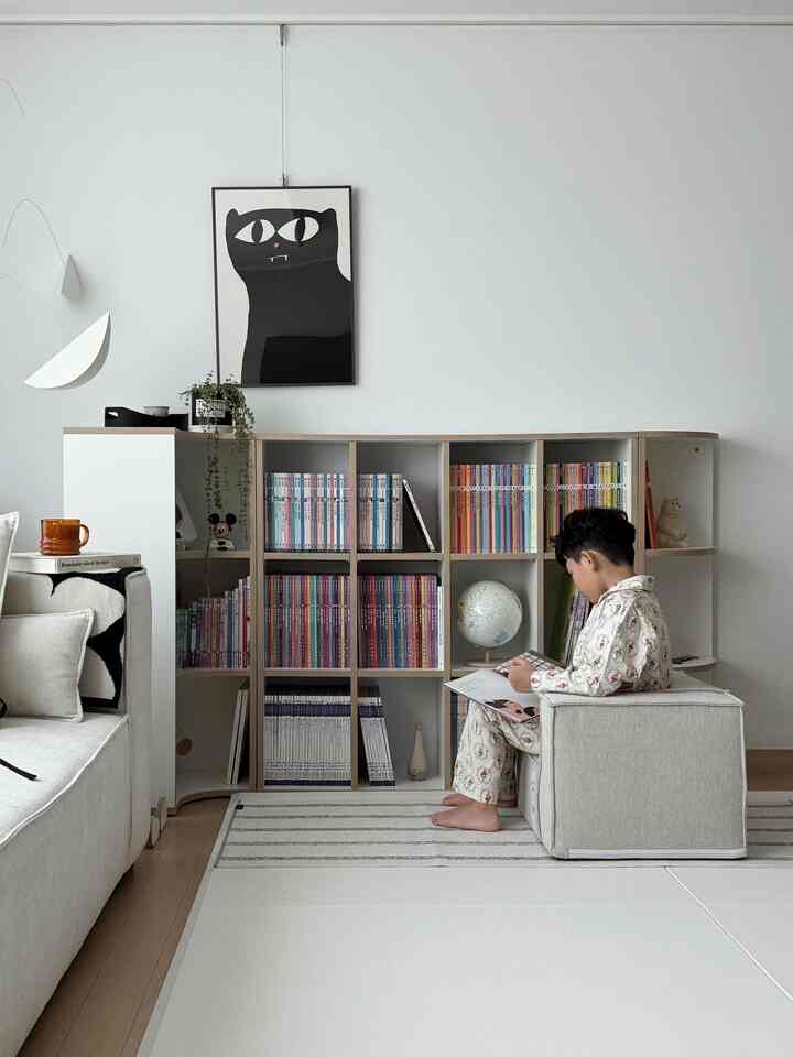 ホワイトとナチュラルトーンのリビング、モジュール式本棚と赤ちゃんが読書するくつろぎ空間