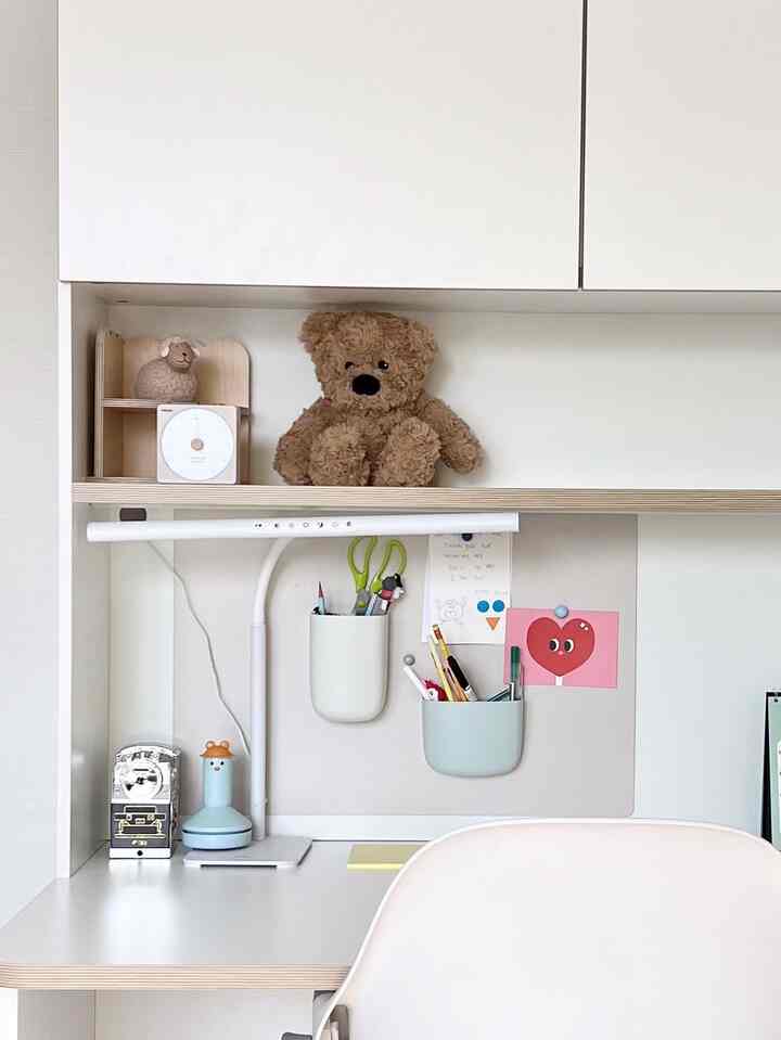 白を基調とした一人用ホームオフィスの子供部屋、整頓されたデスクとテディベアが配置された雰囲気のあるインテリア