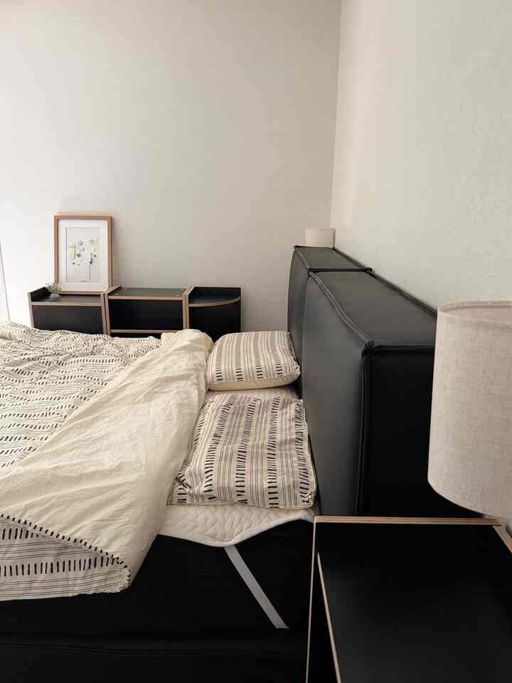 白い壁と黒のベッドフレームが調和したシンプルでナチュラルな雰囲気の寝室