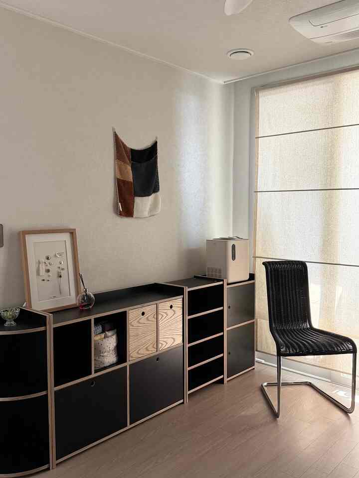 ナチュラルな木目調とブラックの家具が配置されたコンパクトなリビングスペース