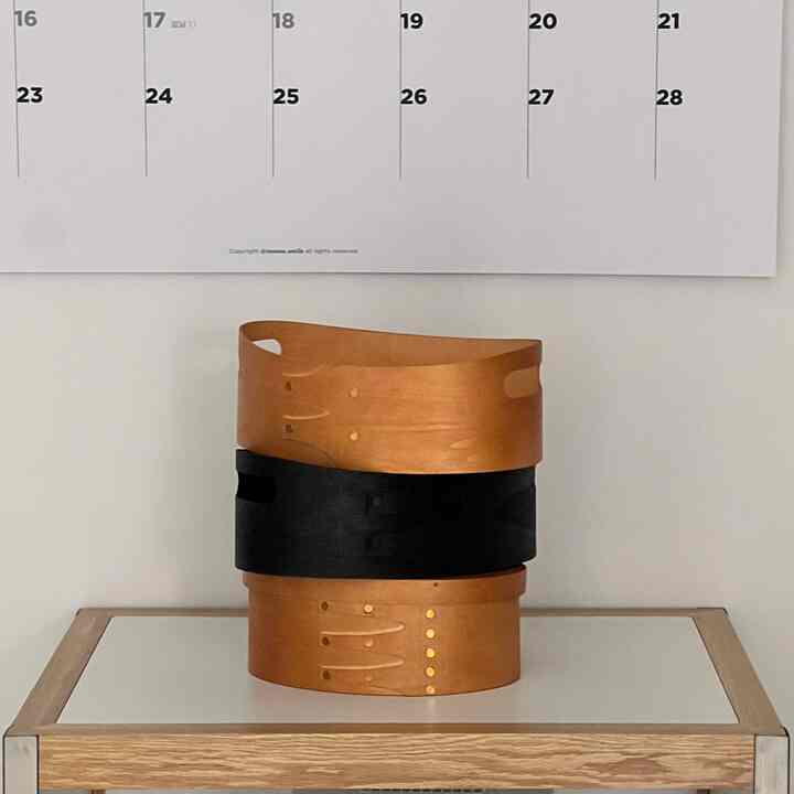 ナチュラルな木目調とブラックのシェイカーボックスが玄関に配置された収納アイテムのあるインテリア。