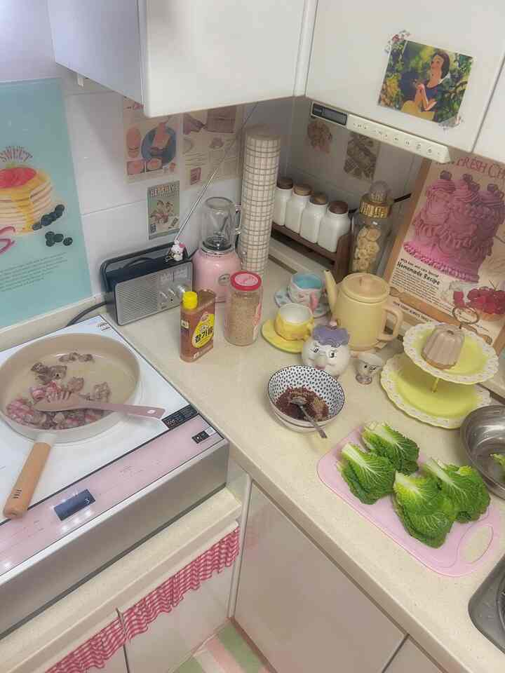 ピンクと緑の色調が印象的なキッチン、レトロでヴィンテージな小物とともに盛り付けられた料理が配置された雰囲気のあるインテリア