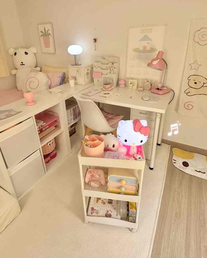白とピンクのトーンでまとめられたホームオフィス兼子供部屋、デスクと移動式トロリー、赤ちゃんのおもちゃが置かれた温かみのある空間