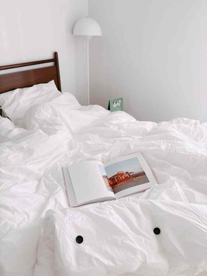 白を基調とした寝室、白い寝具とフロアランプが配置されたシンプルで落ち着いたインテリア