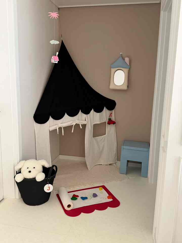 柔らかなベージュ調の子供部屋、ベビーテント、モビール、子供用スツールが置かれた雰囲気のあるインテリア