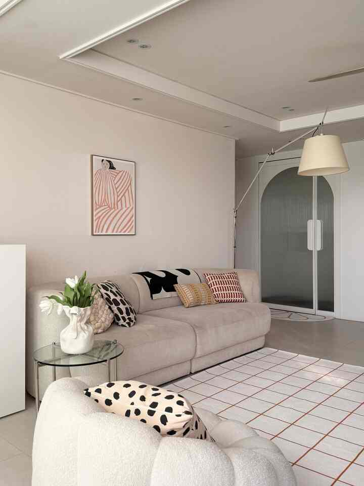 ベージュ調のリビング、ベージュのソファとクッション、フロアランプが配置された雰囲気のあるインテリア