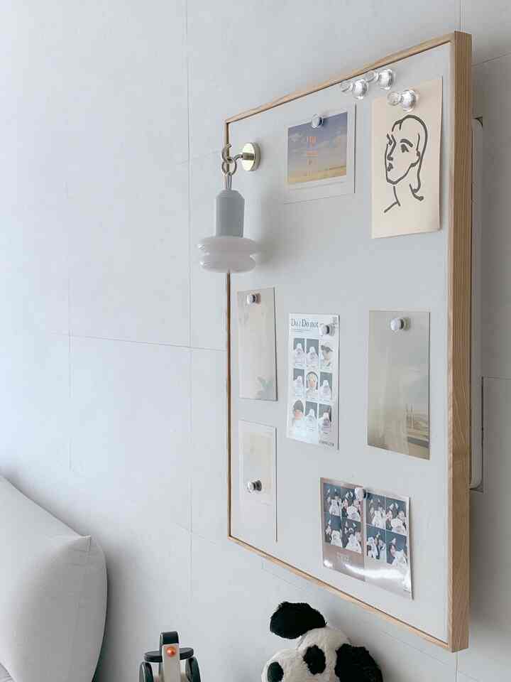 白と木目調のリビング、額縁とソファが調和したシンプルで開放的な雰囲気のインテリア