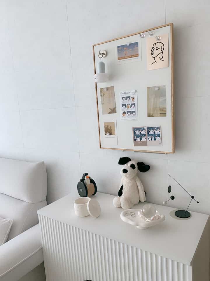 白とナチュラルカラーの壁と家具があるリビング、オブジェや額装アートが配置されたシンプルモダンなインテリア