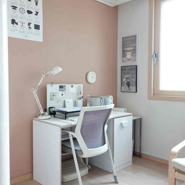 ピンクの壁と白い家具が配置された、すっきりとした居心地の良いホームオフィスの印象的な空間