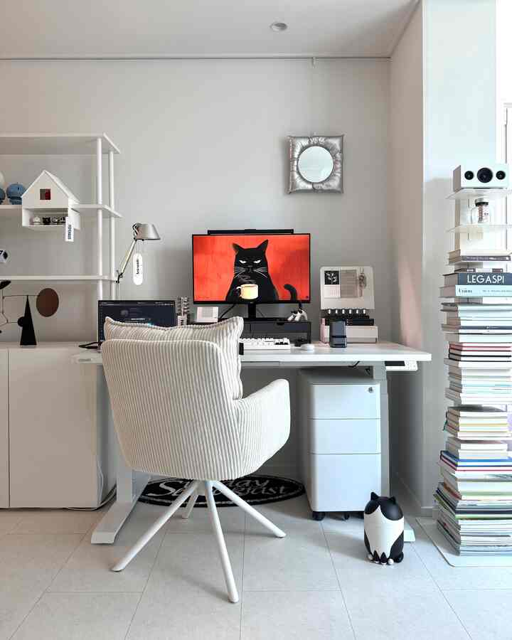 白を基調としたホームオフィス、中央にモニターとデスクが配置され、猫のモチーフがある清潔感のあるワークスペース
