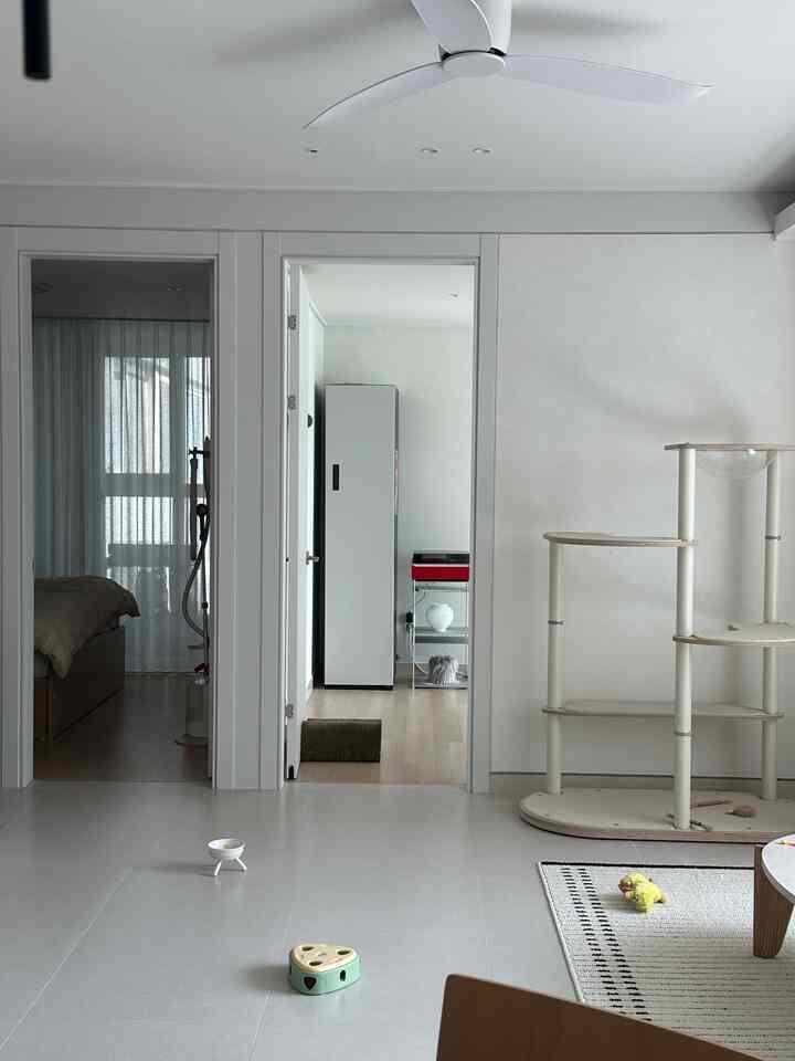 ホワイトと木目調のリビング、キャットタワーとおもちゃが配置されたペットと暮らす空間