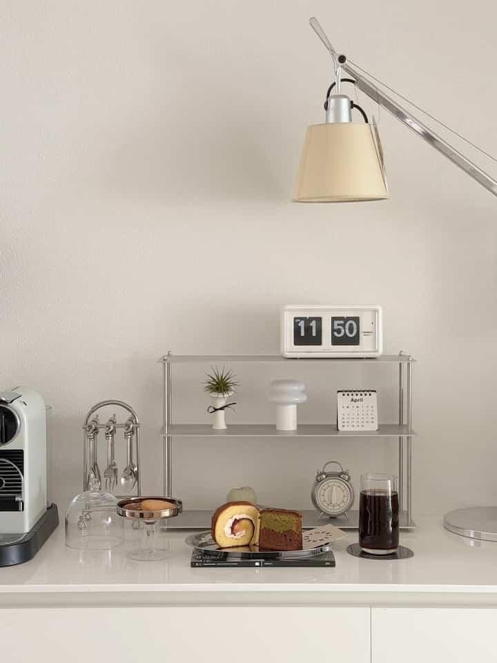 白を基調としたおうちカフェゾーン、モジュールシェルフとコーヒーマシン、デザートが整然と配置されたシンプルでモダンなインテリア