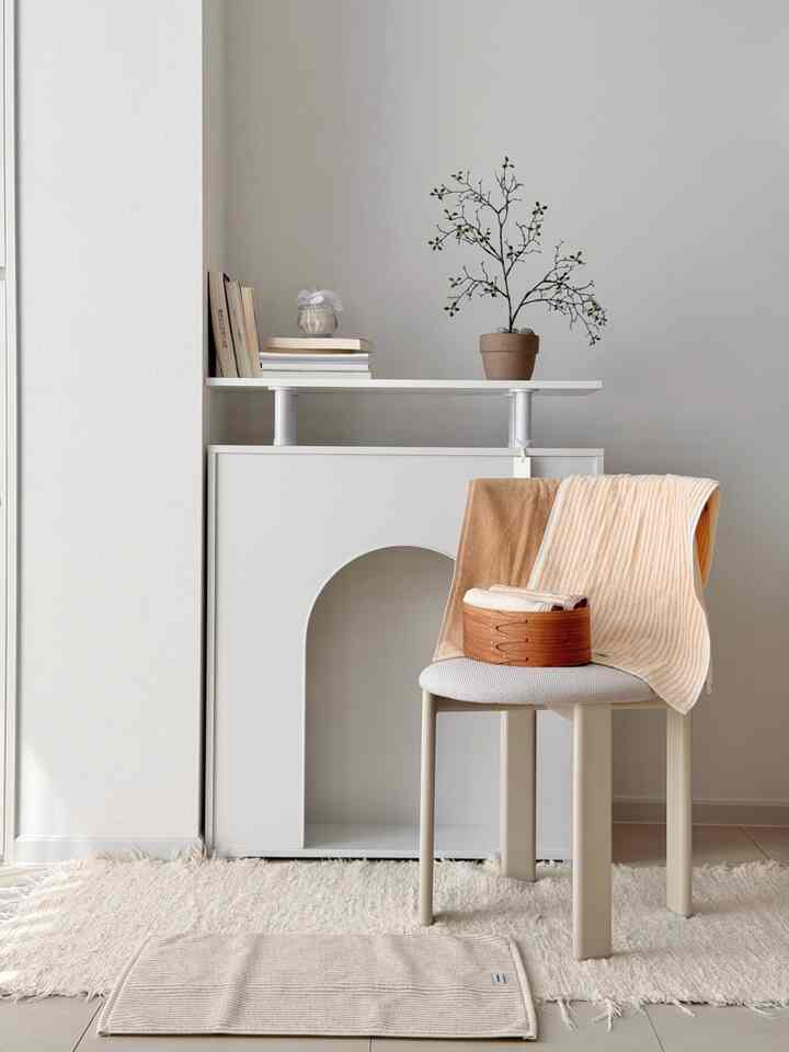 柔らかいベージュ調の落ち着いた浴室またはランドリースペース、椅子とバスケットにストライプと無地のタオルが配置された雰囲気のあるインテリア