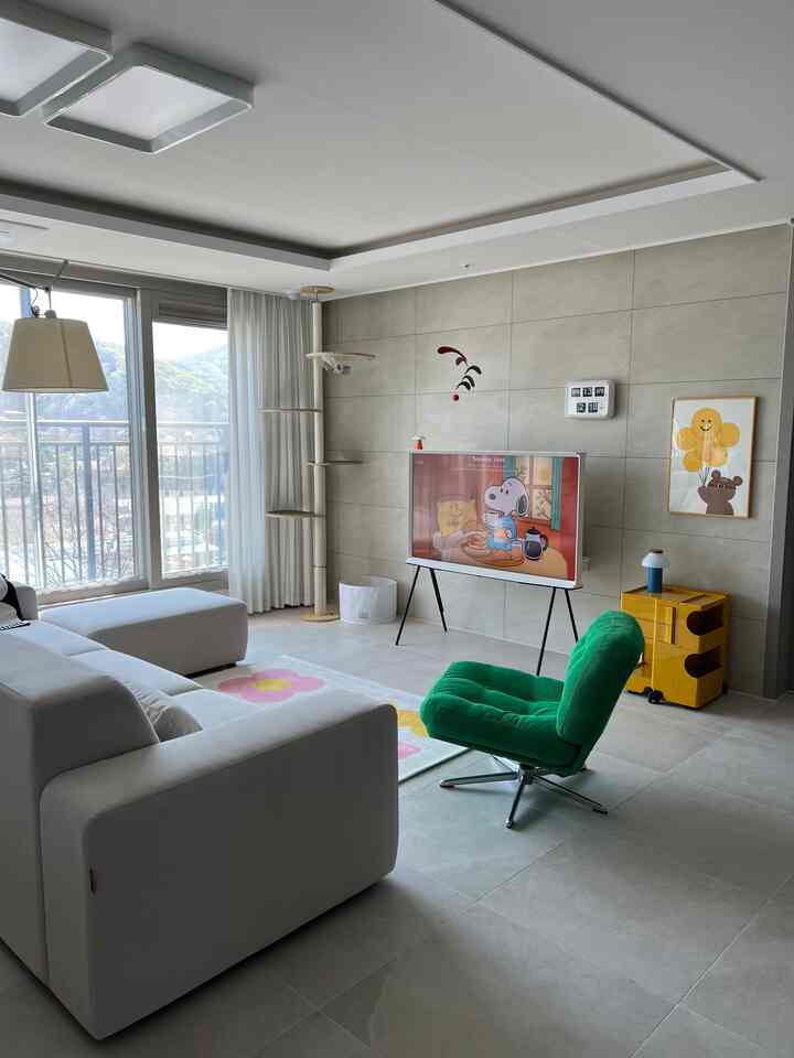 明るいホワイトとナチュラルベージュのリビング、中央にグリーンのワンアームチェアと白いソファが配置された印象的で落ち着いた空間