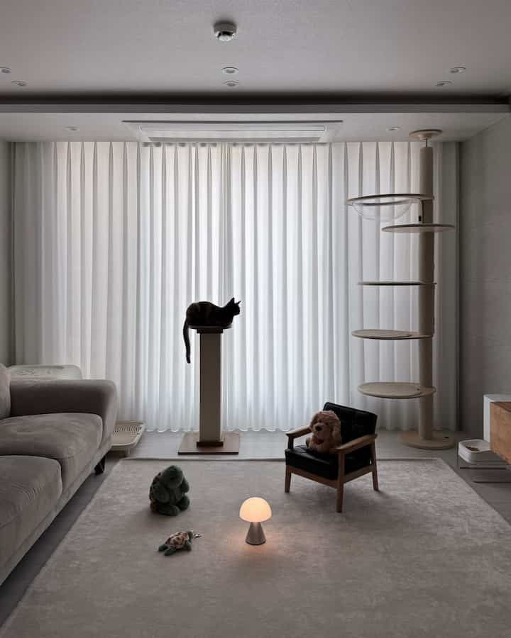 ホワイトとベージュのトーンのリビング、キャットタワーとソファ、ペットに優しい快適な空間