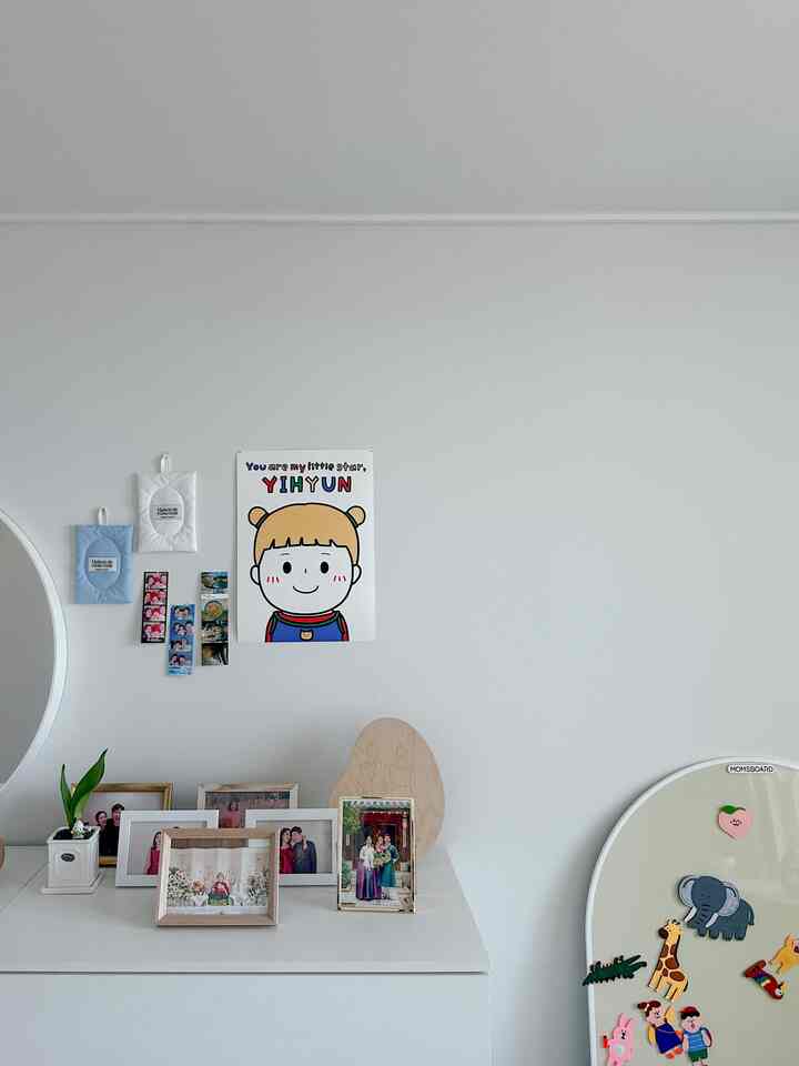 白を基調とした子供部屋、中央壁にかわいいキャラクターポスター、右側にカラフルなマグネットボードが配置された整然とした空間